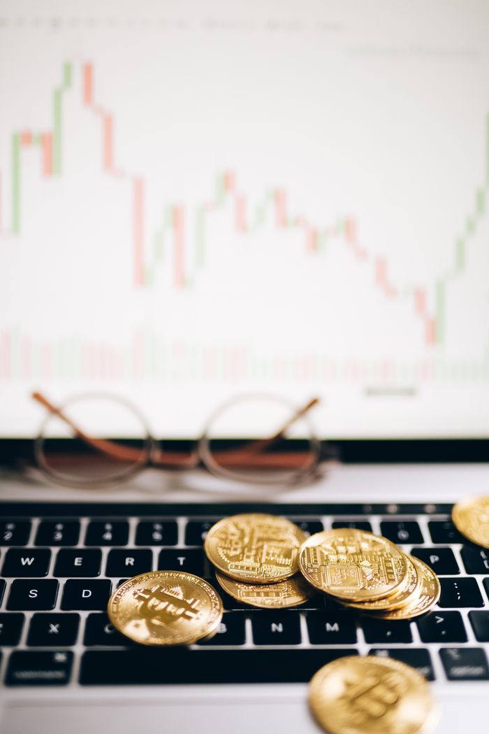 Bitcoin coins on a laptop with a financial chart, representing cryptocurrency investment and analysis.
